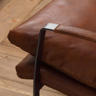 close-up detail of light brown leather seat and steel frame junction on wood floor