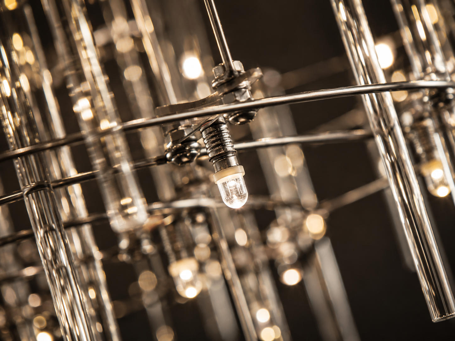 Close-up of the Aura rectangular chandelier featuring warm LED lights reflected through individual clear glass rods.