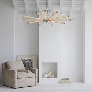 Modern aurora embrace chandelier with brushed metal frame and LED tube arms hanging in a minimalist white living room with a beige armchair and sculptural decor