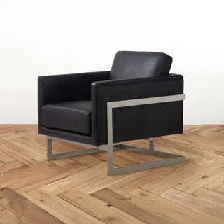 angled view of modern accent chair in new black leather with stainless steel frame on wooden floor