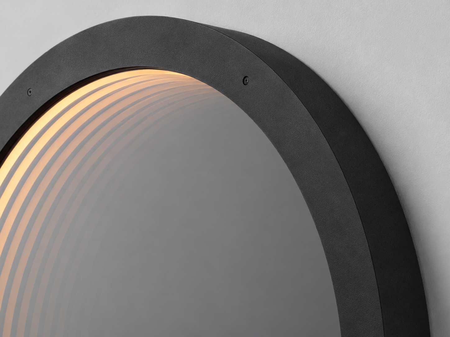 Close-up of the Eclipse round LED mirror with a black frame and warm illuminated edge