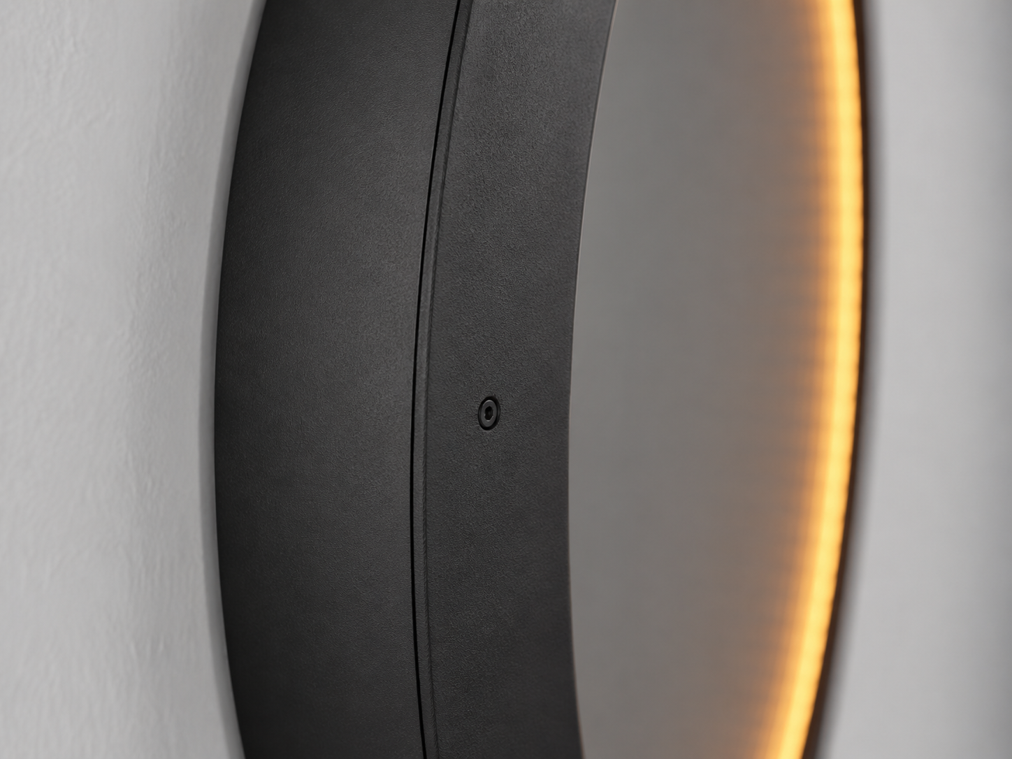 Side profile of the Eclipse round black-framed mirror showing its depth and warm backlighting