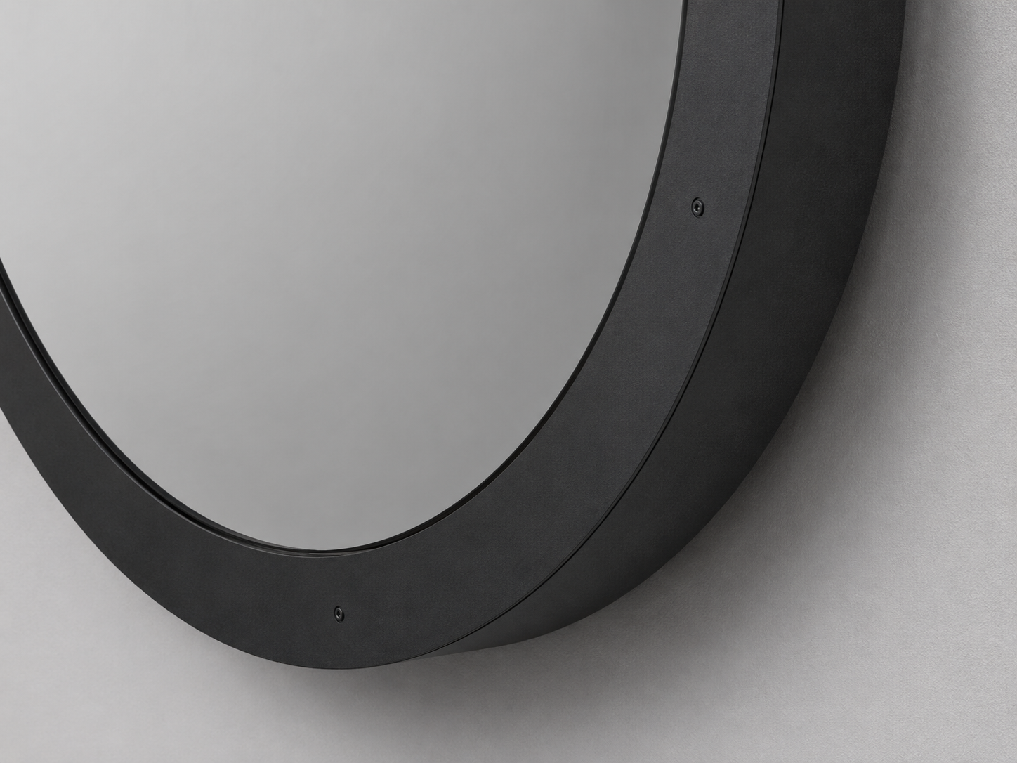 Close-up of the Eclipse round mirror showing the thick black frame and smooth reflective surface unlit