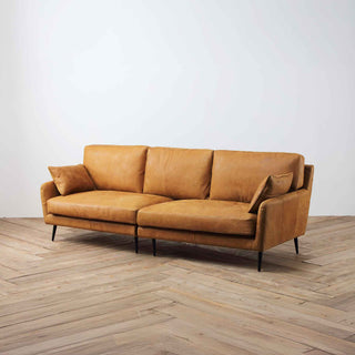 angle view of Essence Collection couch sofa in cognac brown leather, wood floor background, single-seat view