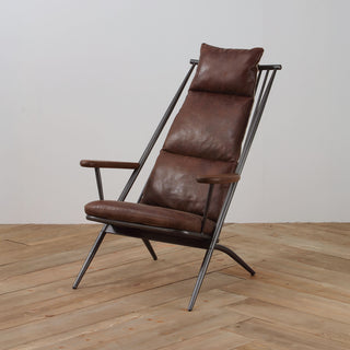 angled view of light brown leather lounge chair with metal frame and wood armrests on wood floor