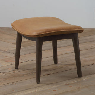 angle view of modern cognac leather lounge footstool with solid wood legs on wood floor