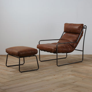 side angled view with wood floor background of modern light brown leather accent chair and ottoman with metal frame