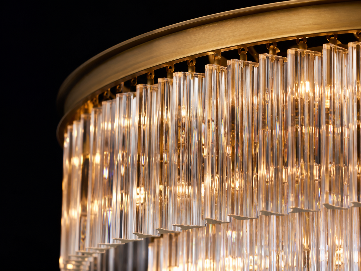 Close-up of illuminated Marais chandelier glass prisms suspended from a brass frame
