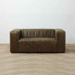 front view of 2-seater ribbed leather sofa in warm whiskey color, white wall and light wood flooring