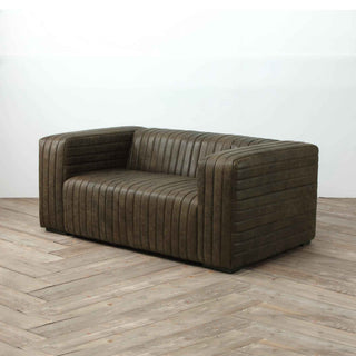 angle view of 2-seater ribbed leather sofa in warm whiskey color, white wall and light wood flooring