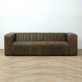 front view of 3-seater ribbed leather sofa in warm whsikey color, placed on light wood flooring with white wall background