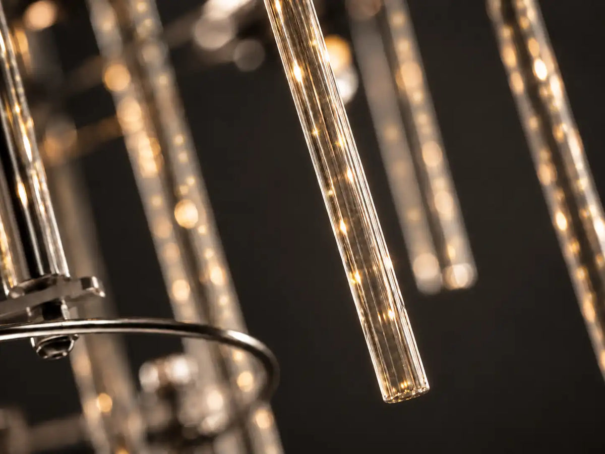Close-up of the Aura chandelier's clear glass rods, each carrying a warm LED glow like a streak of light — contemporary glass rod LED lighting