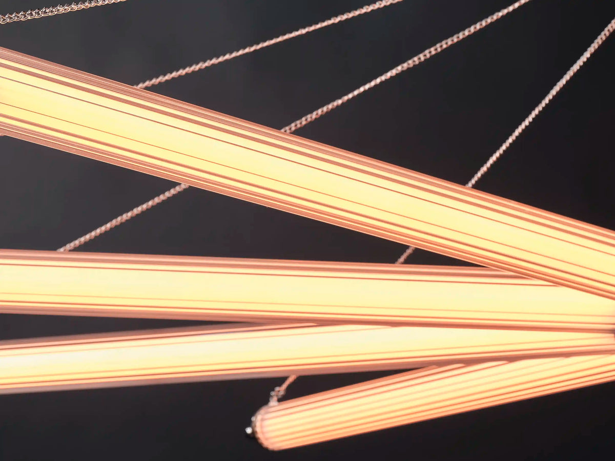 Ribbed glass chandelier arms glowing with warm, evenly diffused light against a dark background.