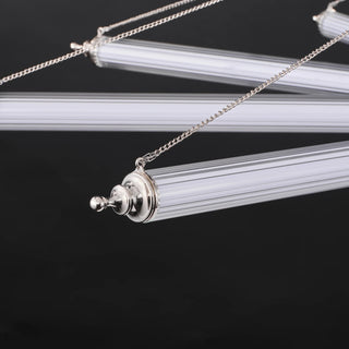 Close-up of unlit ribbed glass tube arms with polished nickel end caps and adjustment chains on the Aurora chandelier.
