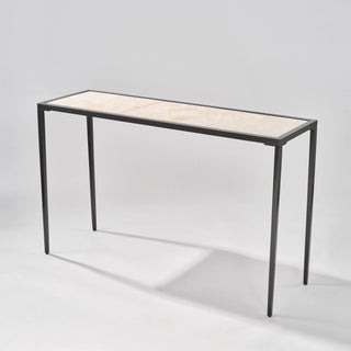 Three-quarter front view of the calcite console table showing its long rectangular top and open black frame.