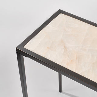 Close-up of the calcite console table corner showing the pale veined stone top set within the slim black frame.