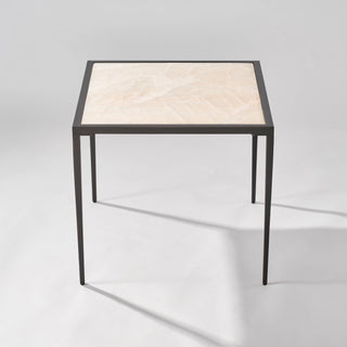 Elevated front view of the calcite side table showing the full square stone top and open black base.