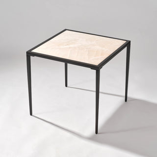 High three-quarter view of the calcite side table showing the tabletop depth and four slim black legs.