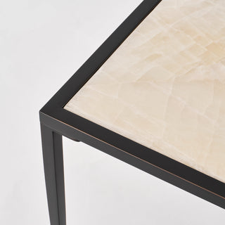 Angled corner detail showing the natural calcite veining, narrow black border, and square leg.