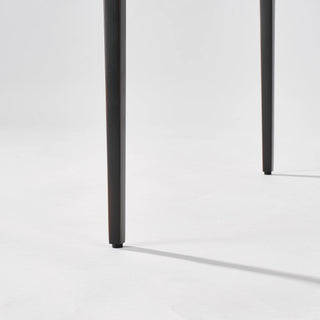 Close-up of the calcite side table’s slim black legs ending in small round floor glides.
