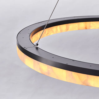 Top detail of the illuminated Calista chandelier showing the suspension cable connection and matte black metal frame.