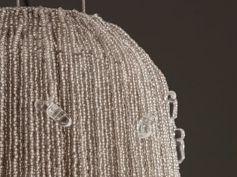 Close-up of the unlit Cascade chandelier: strands of ivory glass beads with clear glass drops at the edge. Ivory beaded chandelier