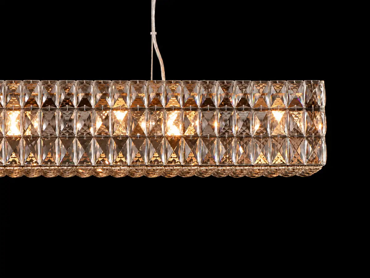 Lattice linear crystal chandelier, close-up: rows of faceted K9 crystal prisms around warm-white bulbs, hung from a cable