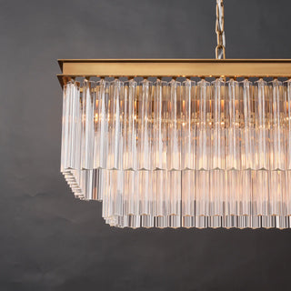 Close-up end view of the illuminated Marais 60-inch rectangular glass chandelier, showing warm light through tiered clear glass rods and a brass-finished frame.