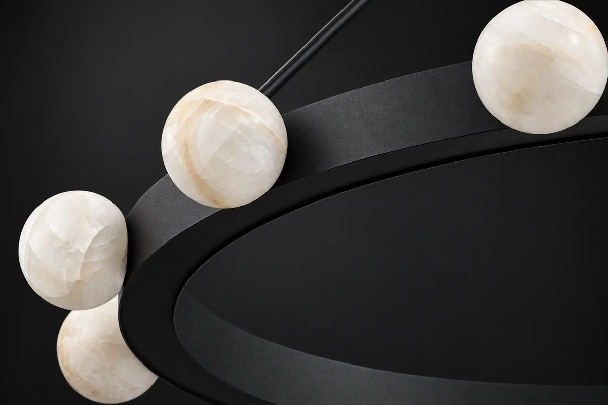 Unlit close-up of natural calcite stone globes on a matte black chandelier ring, each globe with different veining and tone.