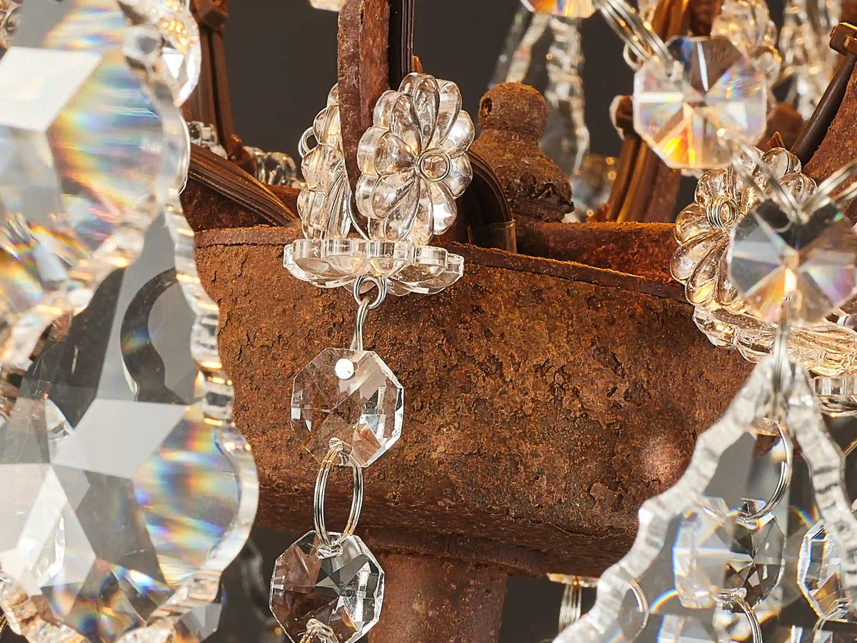 Close-up of the Rustline chandelier’s textured rust-finished iron frame, crystal rosettes, and faceted pendants with rainbow reflections.