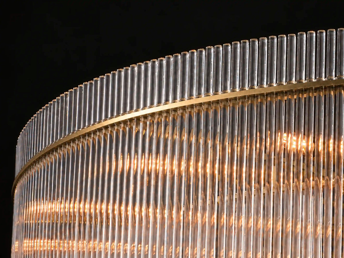 Curved aged brass rim framing clear glass rods on the Timelore chandelier.