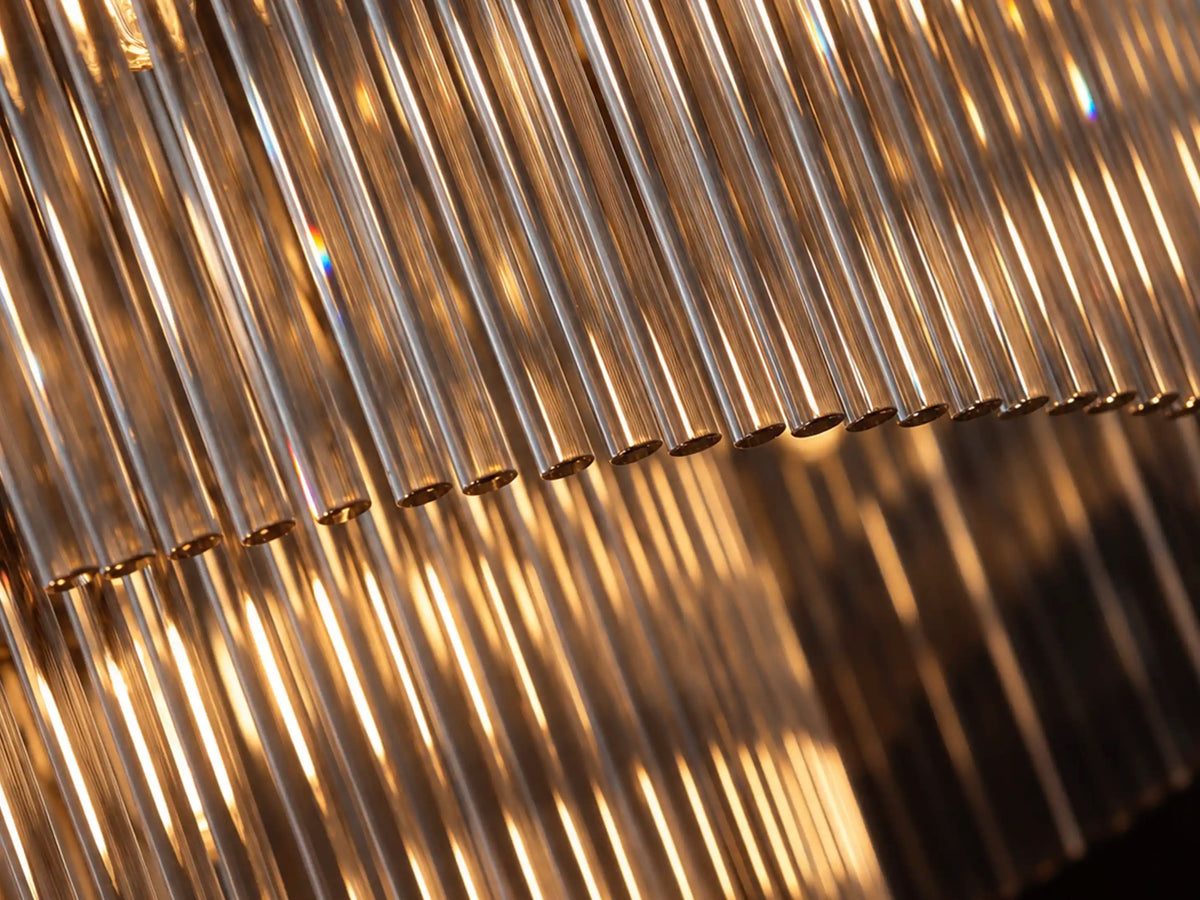 Close-up of Timelore chandelier glass rods reflecting warm light with subtle rainbow highlights.