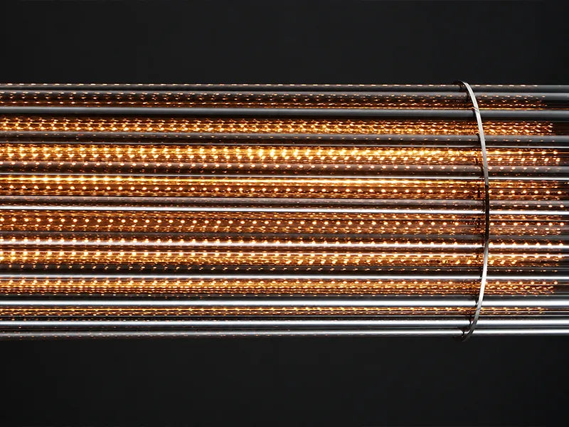 Close-up of the lit Urban Glow chandelier: warm light glowing along rows of glass rods. Dining room linear chandelier