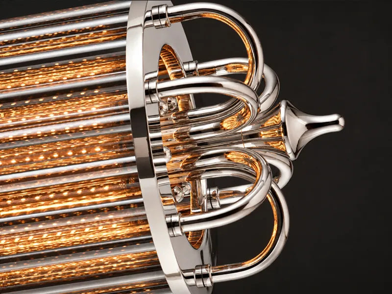 Macro of the Urban Glow chandelier's nickel-finish scrolls curving over the lit glass rods at one end. Linear pendant light for home bar