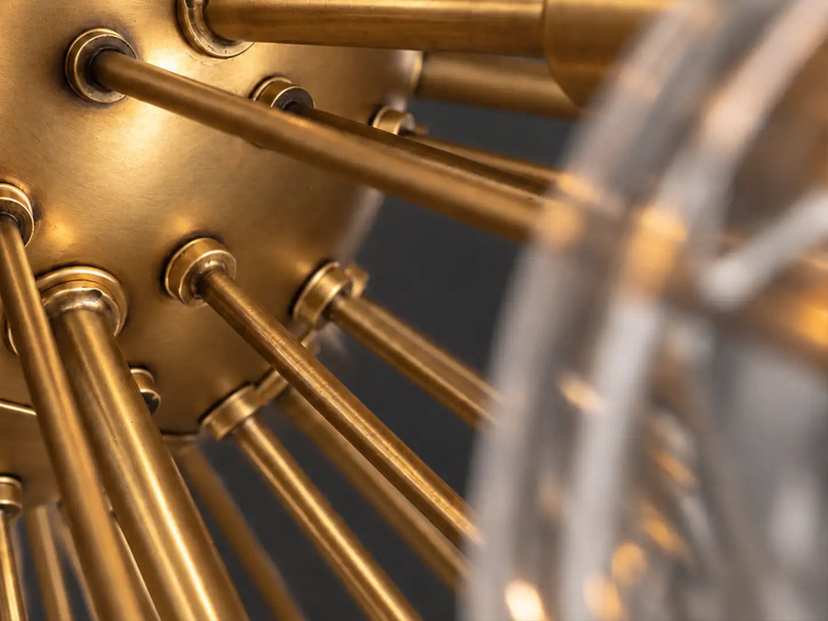 Close-up of a glass disc chandelier’s brass-finish central hub and radiating arms, showing fine surface texture and soft metallic reflections.