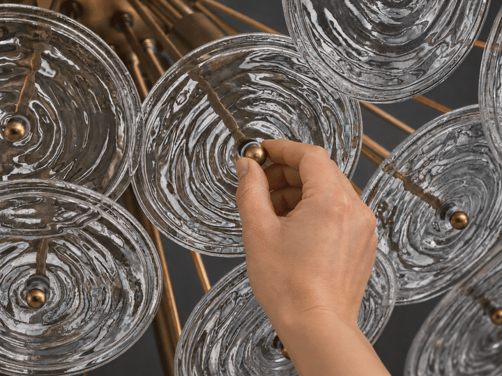 Close-up of a brass chandelier with textured glass discs, cycling from unlit to soft and bright warm light.