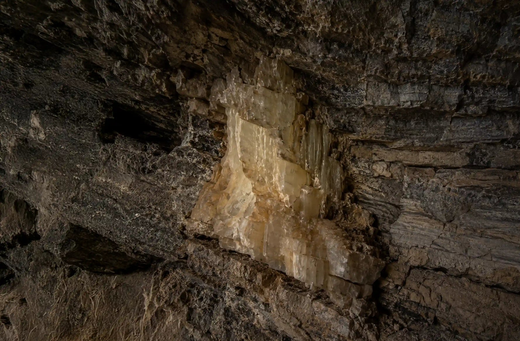 Natural calcite stone embedded in rock, highlighting the raw mineral texture and distinctive translucent veining.