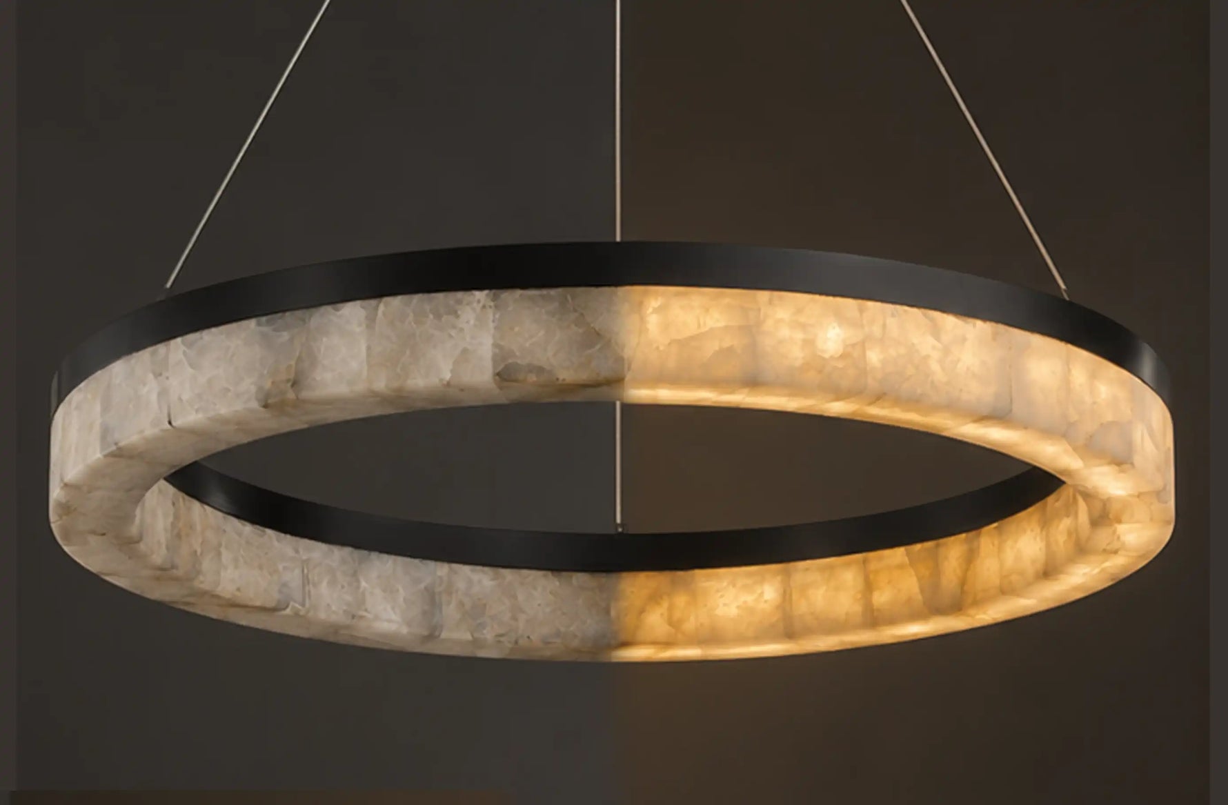 Illuminated calcite ring chandelier featuring natural stone panels, warm ambient light, and slim suspension cables.