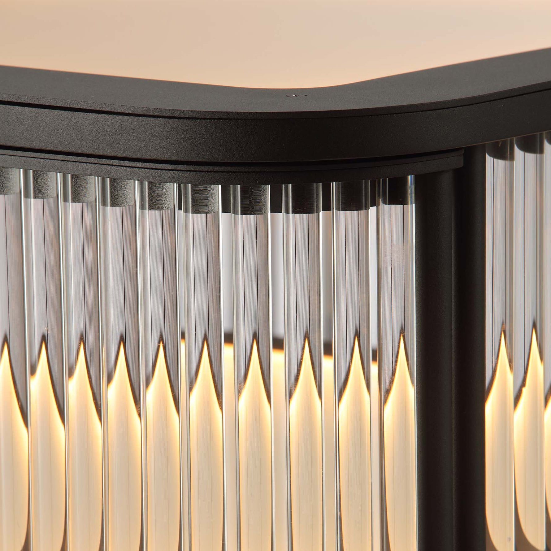 close-up top view of illuminated bar matte black metal frame cabinet with fluted glass and warm LED lighting