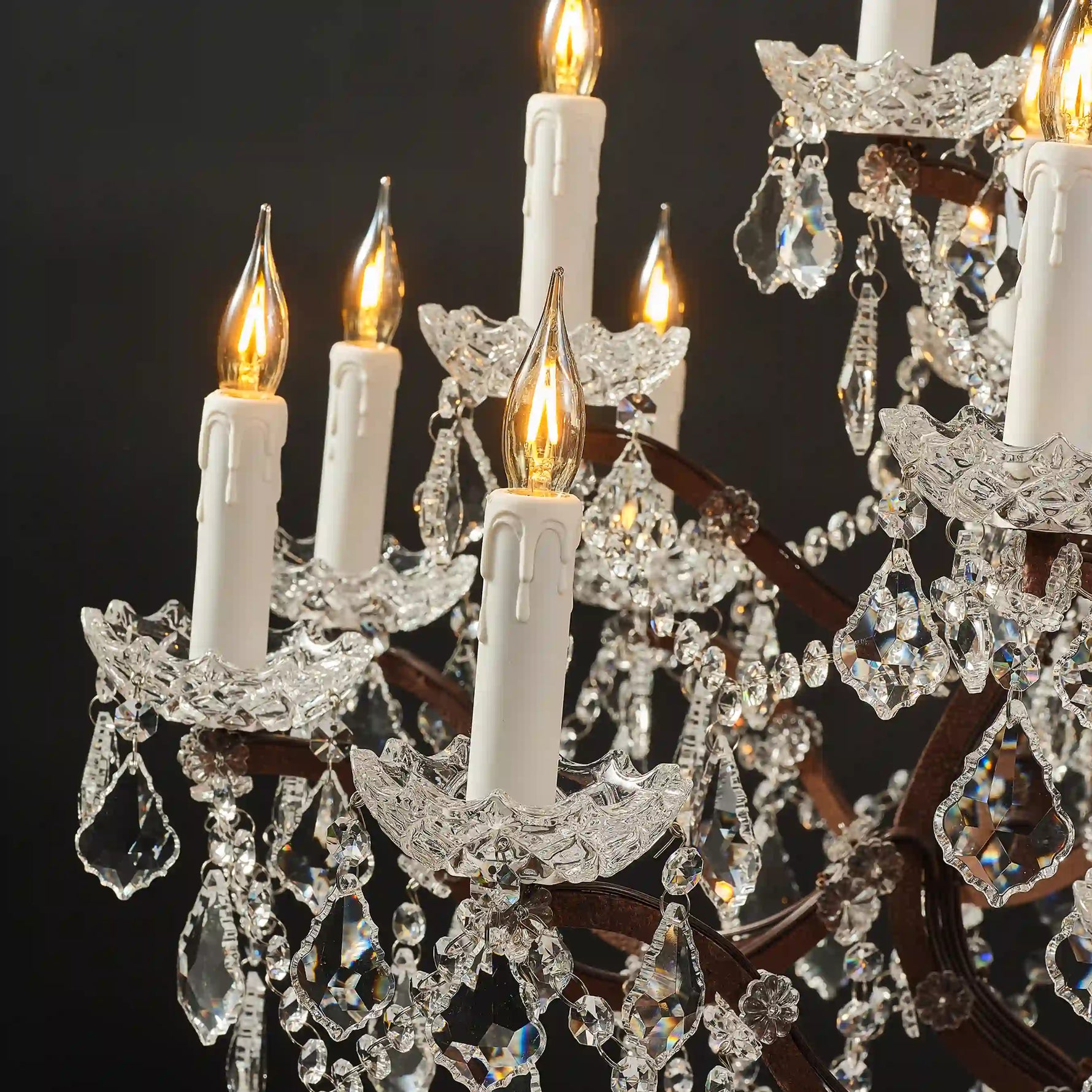 Moorizon Rustline 25-light crystal chandelier close-up view with warm candle lights, carved iron arms, and crystal drops, lit detail view, black background when lit