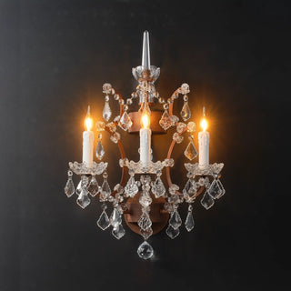 Warmly lit Moorizon Rustline 3-light wall sconce with three candle-style lights, hanging crystal drops, and antique-style iron details on a black background