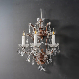 Unlit Moorizon Rustline 3-light wall sconce with candle sleeves, curved iron arms, and crystal accents on a gray background