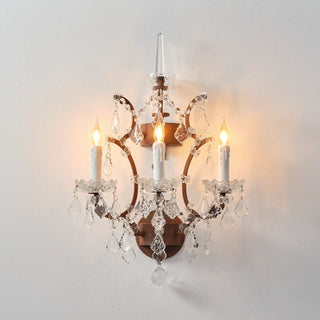 Warmly lit Moorizon Rustline 3-light wall sconce with candle-style lights, crystal drops, and antique-style iron details on a white background