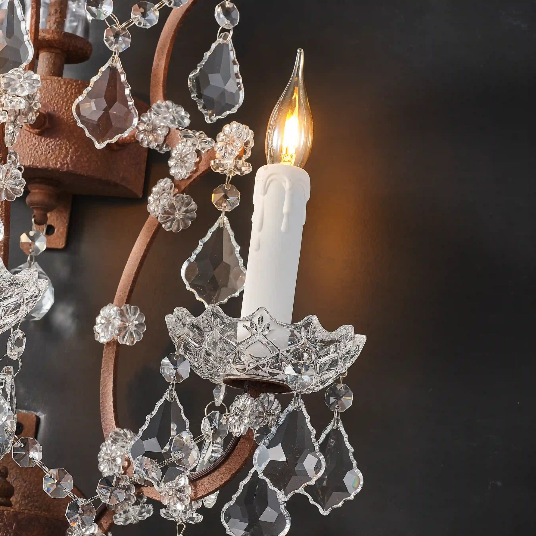 Warmly lit Moorizon Rustline 3-light wall sconce detail with candle-style bulb, crystal drops, and antique-style metal arms