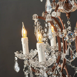 Moorizon Rustline 6-light crystal chandelier with candle-style bulbs, iron arms, and crystal drops, light on with black background detail view