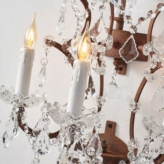 Warmly lit Moorizon Rustline 3-light wall sconce detail with candle-style bulbs, hanging crystal accents, and curved metal arms