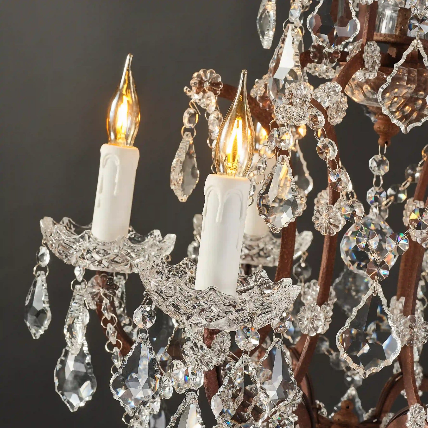 Rustline crystal floor lamp with candle-style lights and cascading crystal details, light on in a black background. 