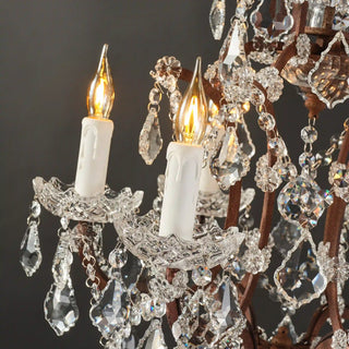 Rustline crystal floor lamp with candle-style lights and cascading crystal details, light on in a black background. 
