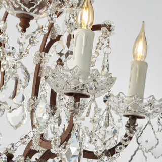 Detail view of Rustline crystal floor lamp with candle-style bulbs and hanging crystal, light on in white background. 