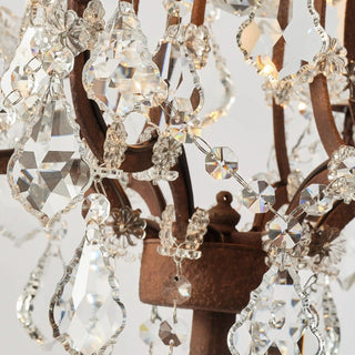 Close-up of Rustline crystal floor lamp with clear crystal drops and metal frame in white background. 